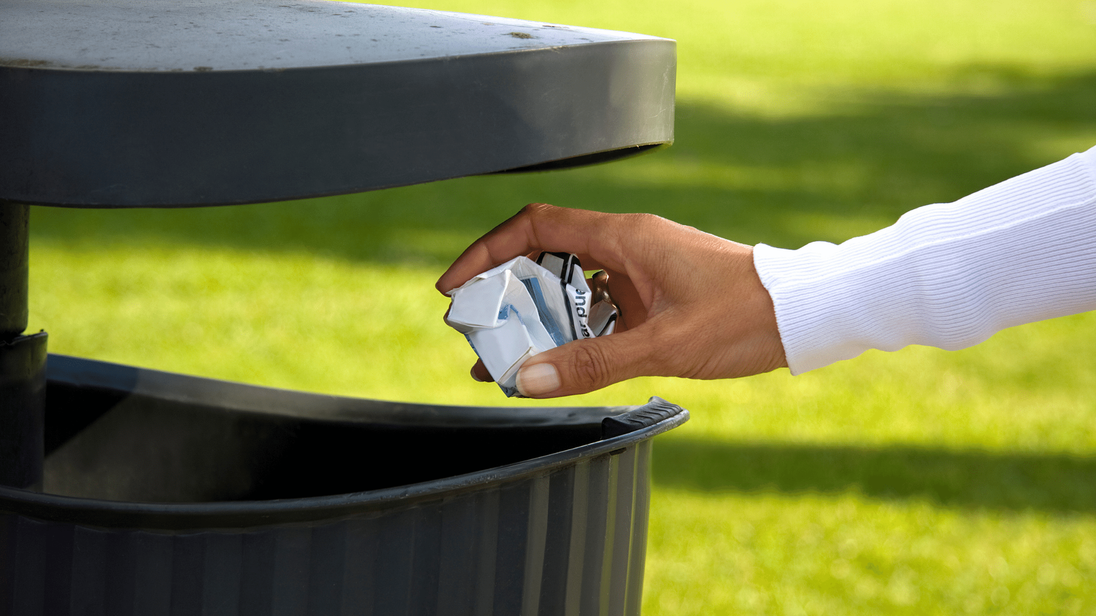 image showing a waste bin and a hand about to throw a ball of paper into the bin opening