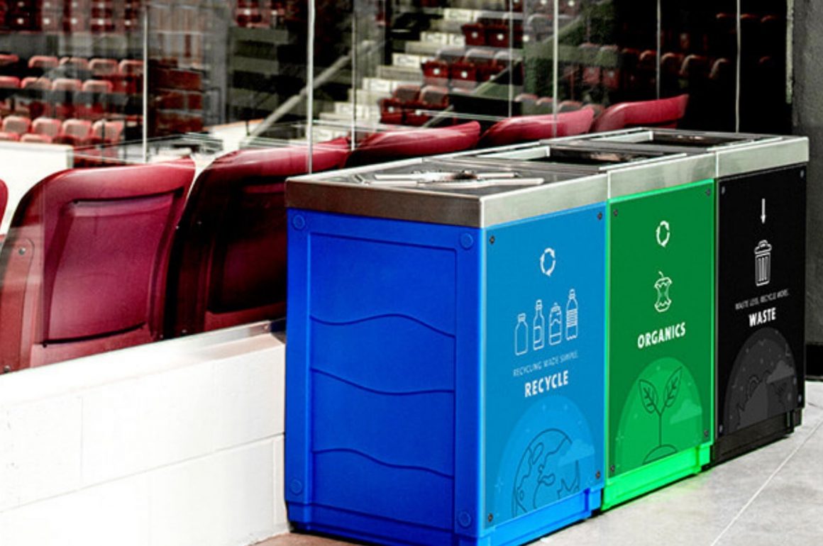 Photograph showing three Busch bins outside a venue with red arena seats in the background