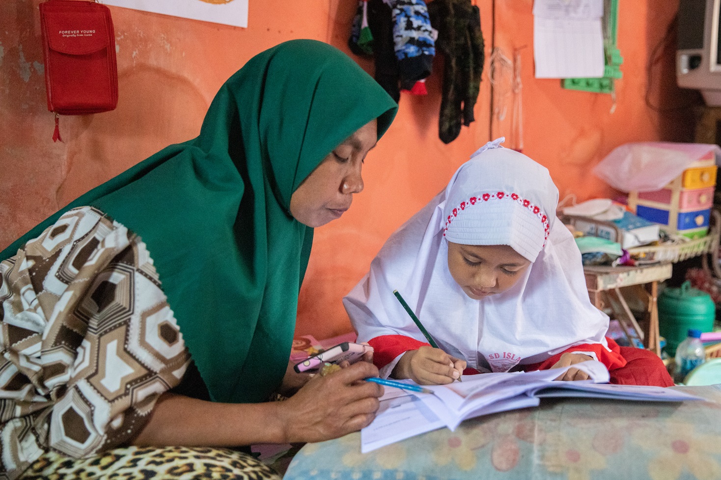 Atmawati accompanies her daughter study at their home in Bali, Indonesia. Photo Courtesy of Plastic Bank
