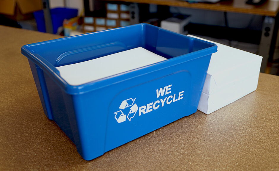 Busch Systems Deskside Recycler container in blue with mobius loop we recycle graphic filled with paper