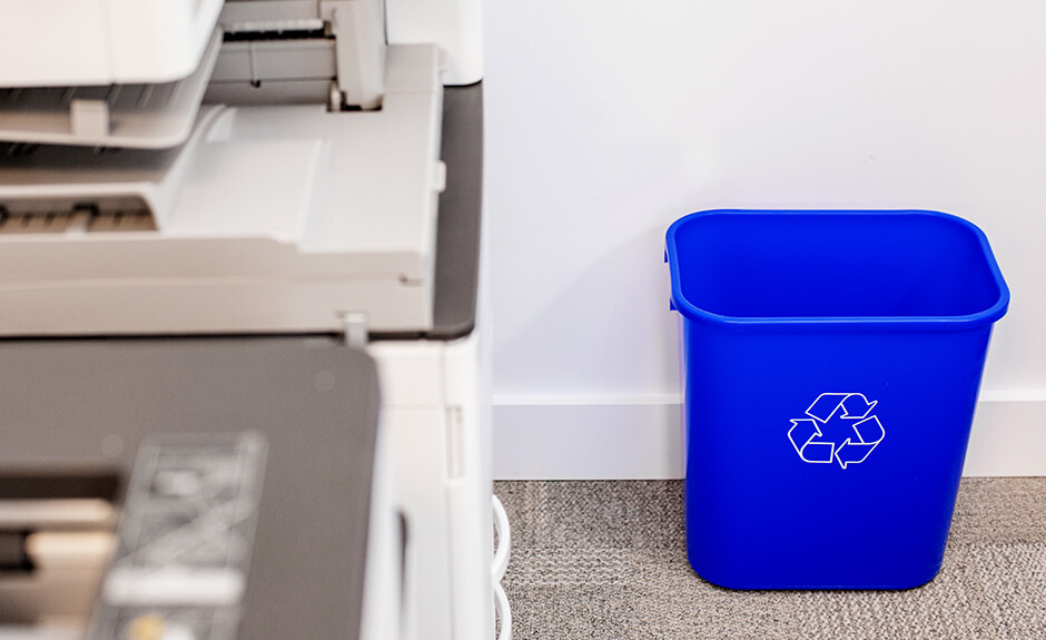 Busch Systems blue Recycling and Waste basket with mobius loop symbol in an office copy room