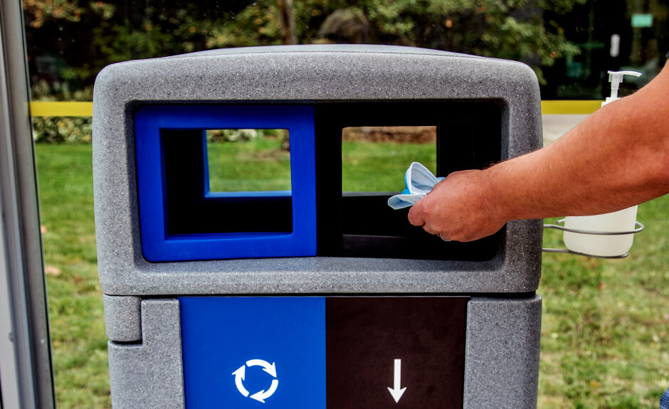 Someone putting a disposable mask into the waste stream of the Busch Systems Expression container