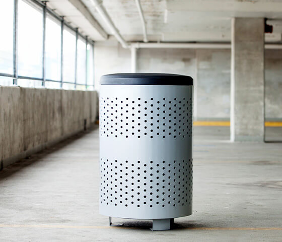 Busch Systems Portland single waste container with black full open lid secured to the ground in a parking garage