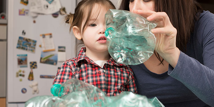 Little girl collecting plastic for recycling with her mother