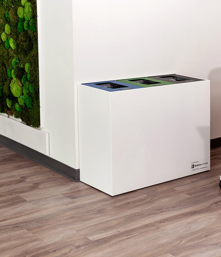 Minimalist white three-stream recycling and waste station by Busch Systems positioned against an office wall.