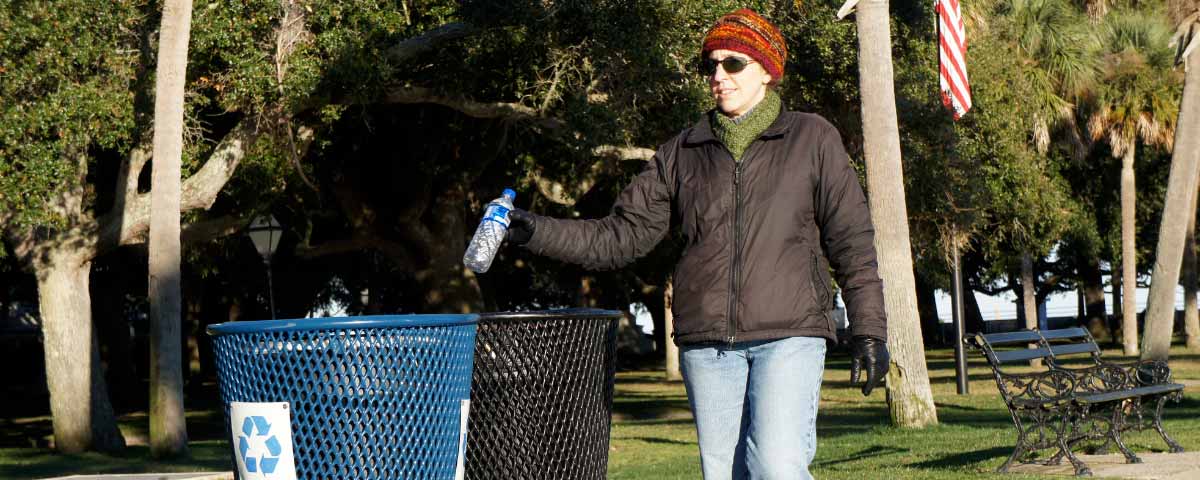 woman putting a bottle in a recycling container outside