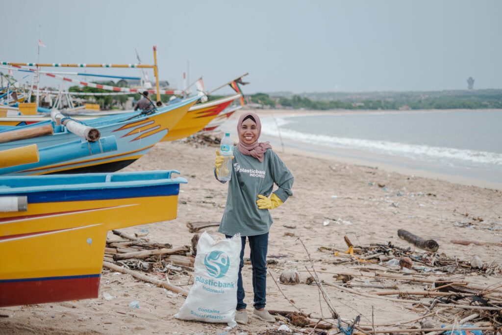 Plastic Bank collector in Indonesia on the beach showing a bottle that was just collected
