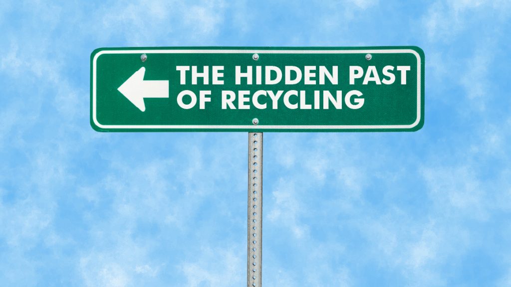 A green road sign with a white left arrow and text that reads THE HIDDEN PAST OF RECYCLING against a blue sky with light clouds.