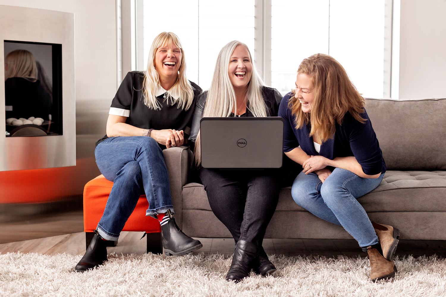3 woman smiling, one is holding a laptop