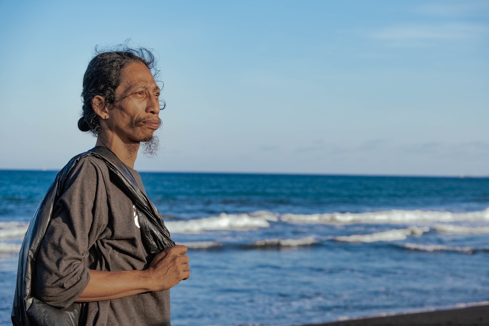 man carrying garbage bag out of the beach