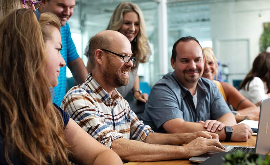a group of people staring at the laptop and smiling