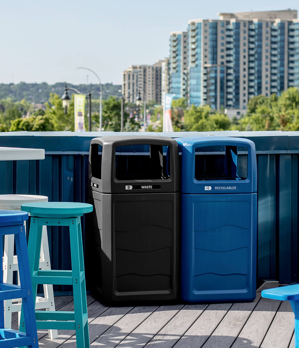 black and blue post-consumer recycled plastic waste and recycling bins outside on a rooftop patio