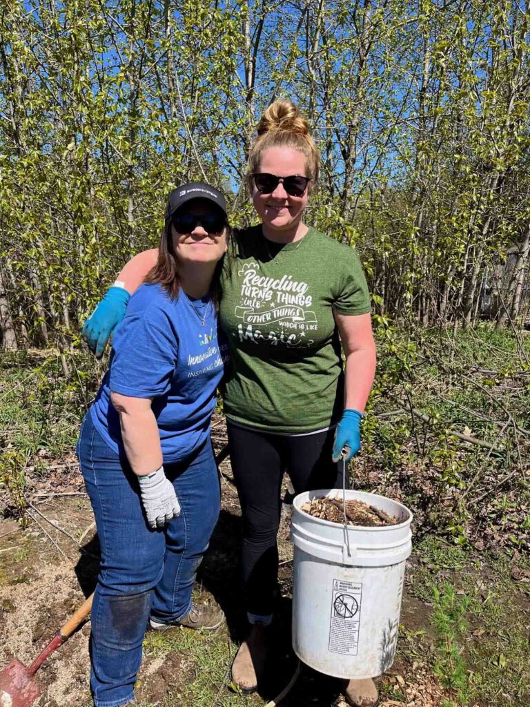 two women outside on a sunny day planting trees