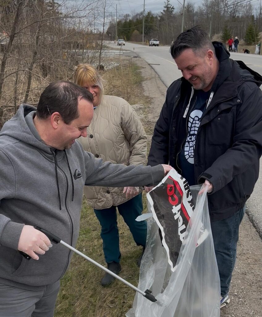 group of people picking up trash on the side of a road