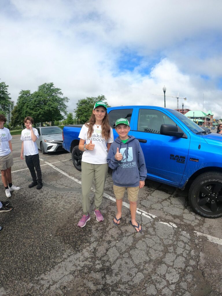 two youth with thumbs up standing beside blue pickup truck
