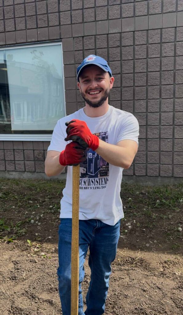 man holding a shovel wearing a blue hat and jeans