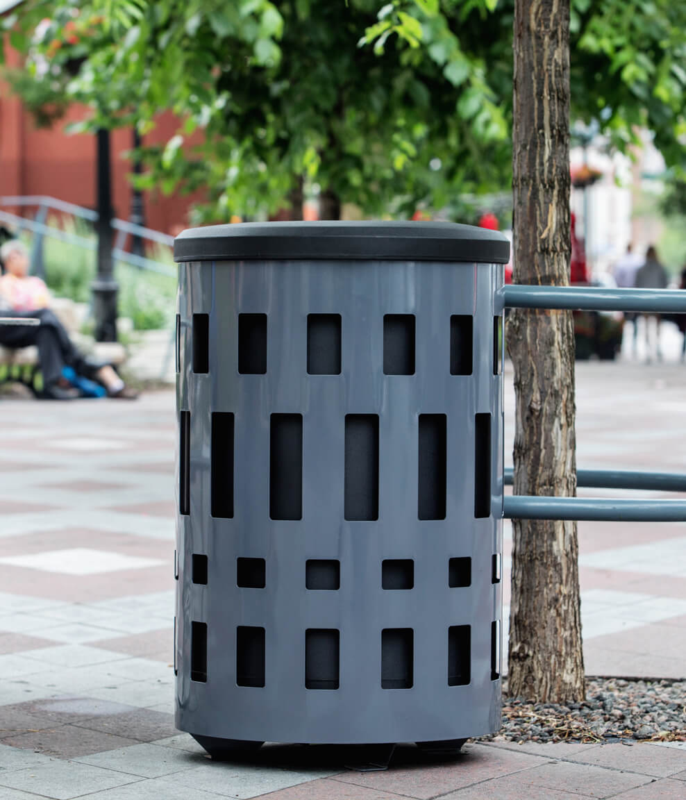 grey metal outdoor waste container with a black plastic lid in a city park
